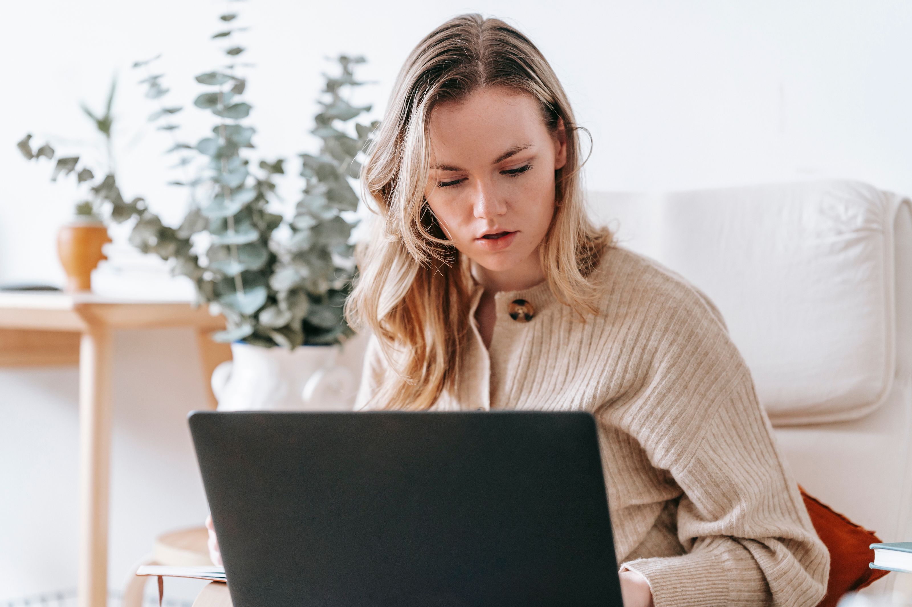 A freelancer working on a laptop at a bright home desk.